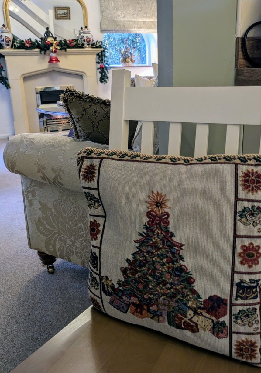 Cosy living room decorated for Christmas with a festive pillow, fireplace garland, and holiday decor.