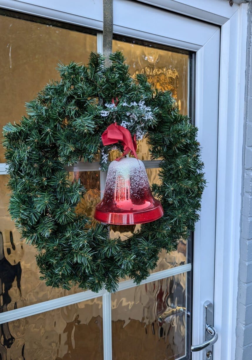 The Saddlery Holiday Cottage front door decorated with a green and red Christmas wreath.