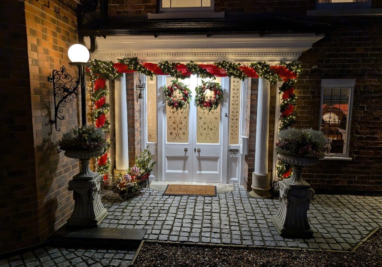 Sadlers front door, festively adorned for Christmas with garlands, twinkling lights and wreaths.